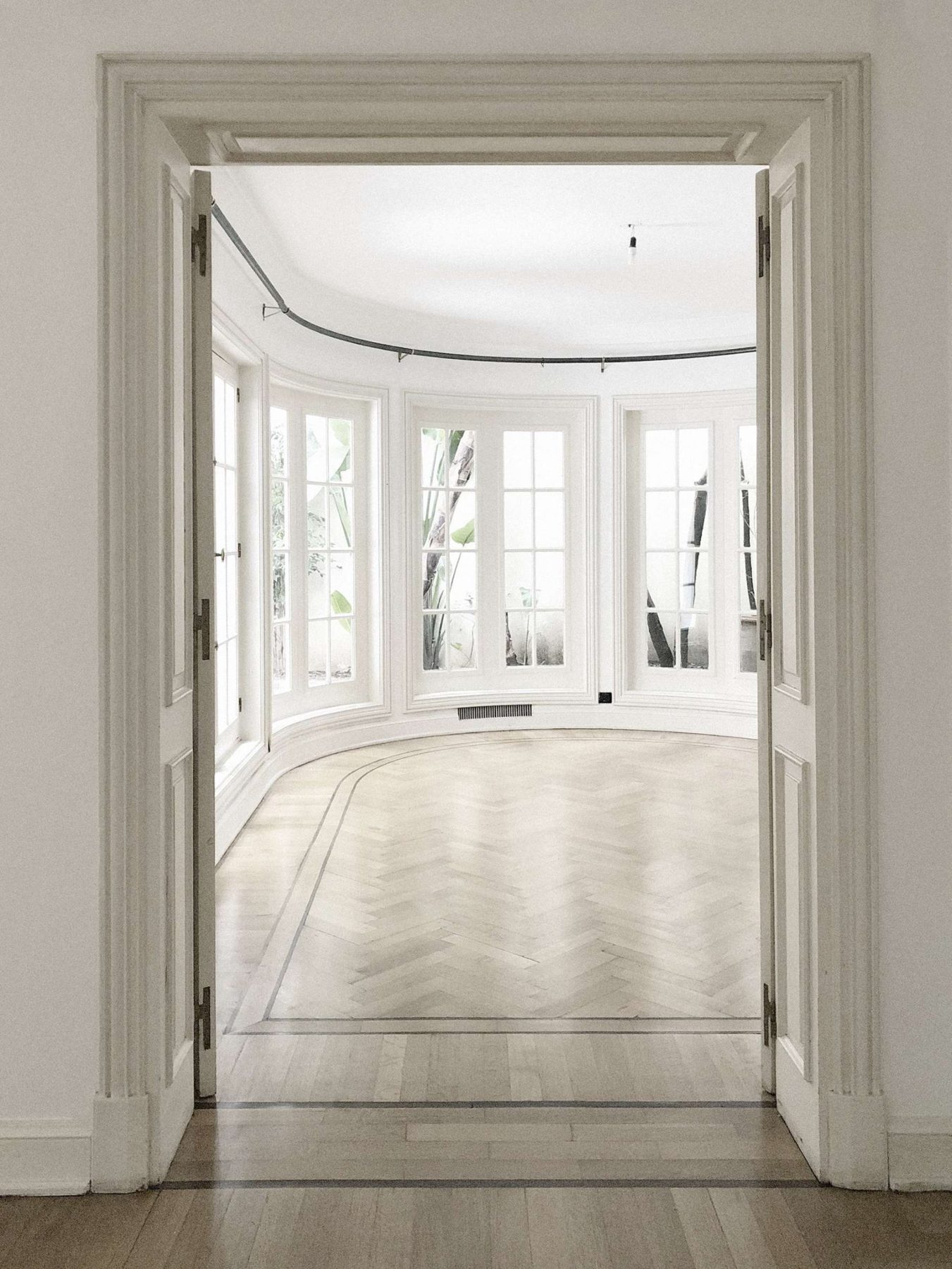 Ombú St. House: a curved bay of French windows over restored herringbone floors